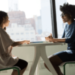 two women talk at table